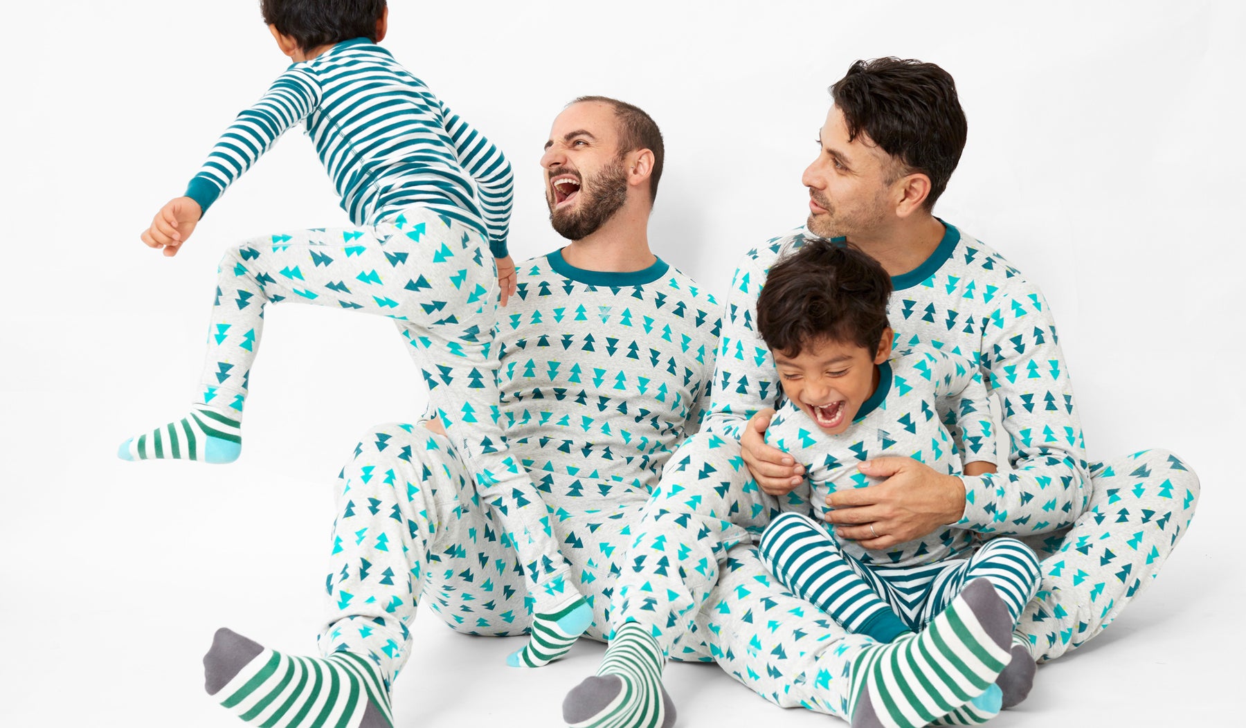 two dads with twin boys wearing matching tree pajamas