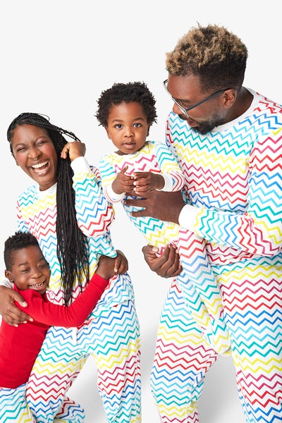 parents and two children smile and laugh together in matching rainbow chevron pajamas